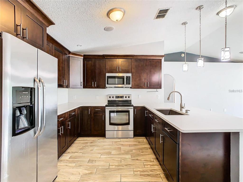 3194 Windmill Point Boulevard Kissimmee, FL 34746 - Photo 10 of 32 a kitchen with stainless steel appliances granite countertop a sink and stove top oven