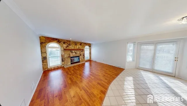 a view of an empty room with window and wooden floor