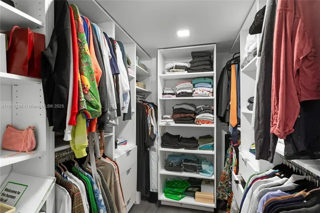 a view of walk in closet with clothes and shoes