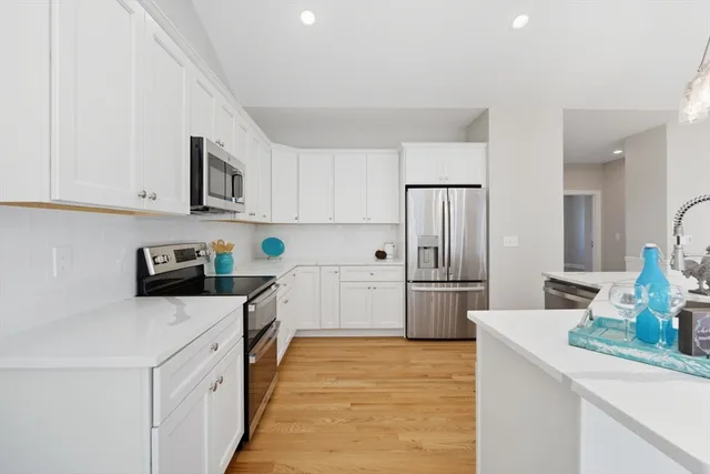 a kitchen with a sink a stove top oven a refrigerator and white cabinets