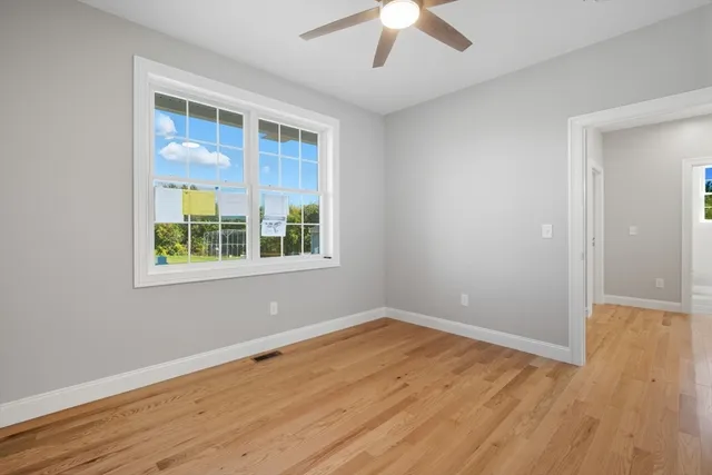 a view of an empty room with wooden floor and a window