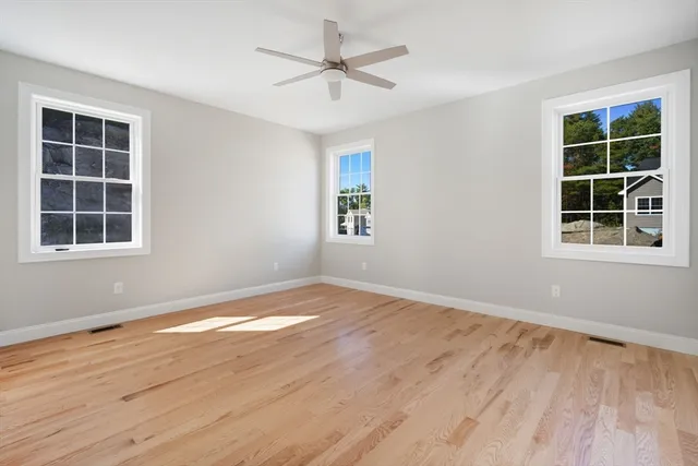a view of empty room with wooden floor and fan
