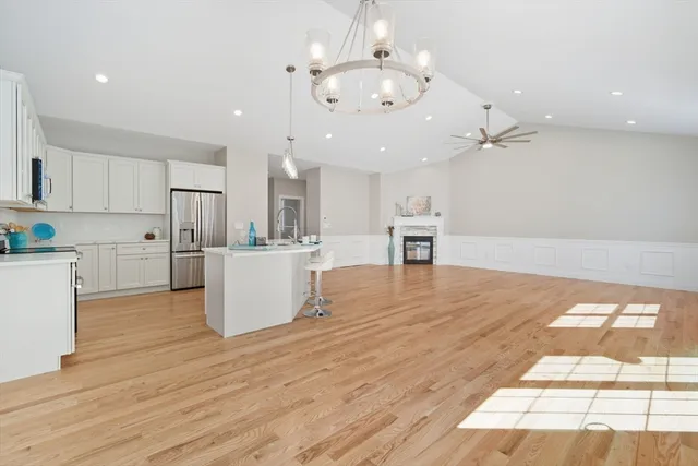 a large kitchen with kitchen island a stove a sink dishwasher and a dining table with wooden floor