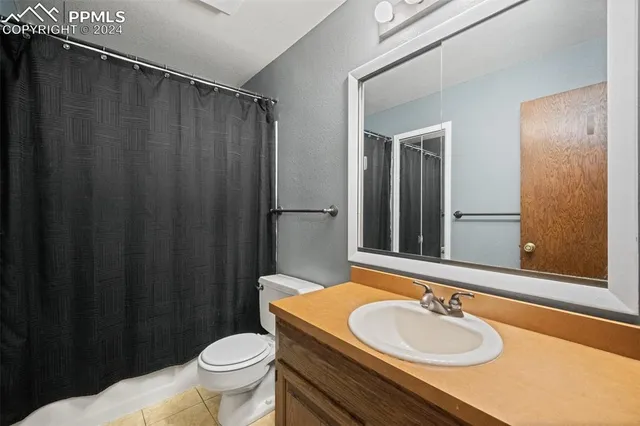 a bathroom with a sink a toilet a mirror and shower curtain