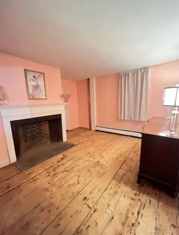 a view of empty room with wooden floor and fireplace