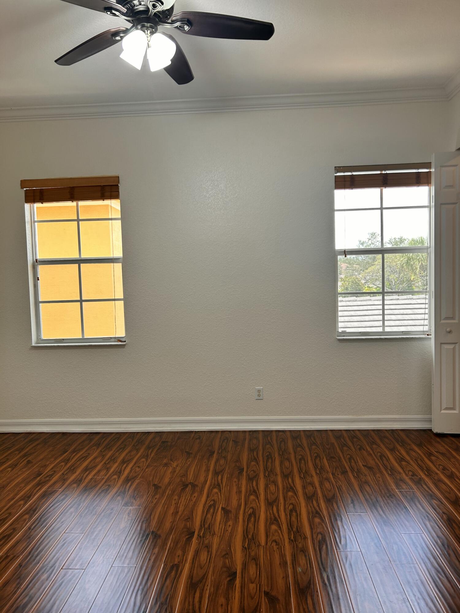 134 Ennis Lane Jupiter, FL 33458 - Photo 8 of 19 an empty room with wooden floor chandelier fan and windows