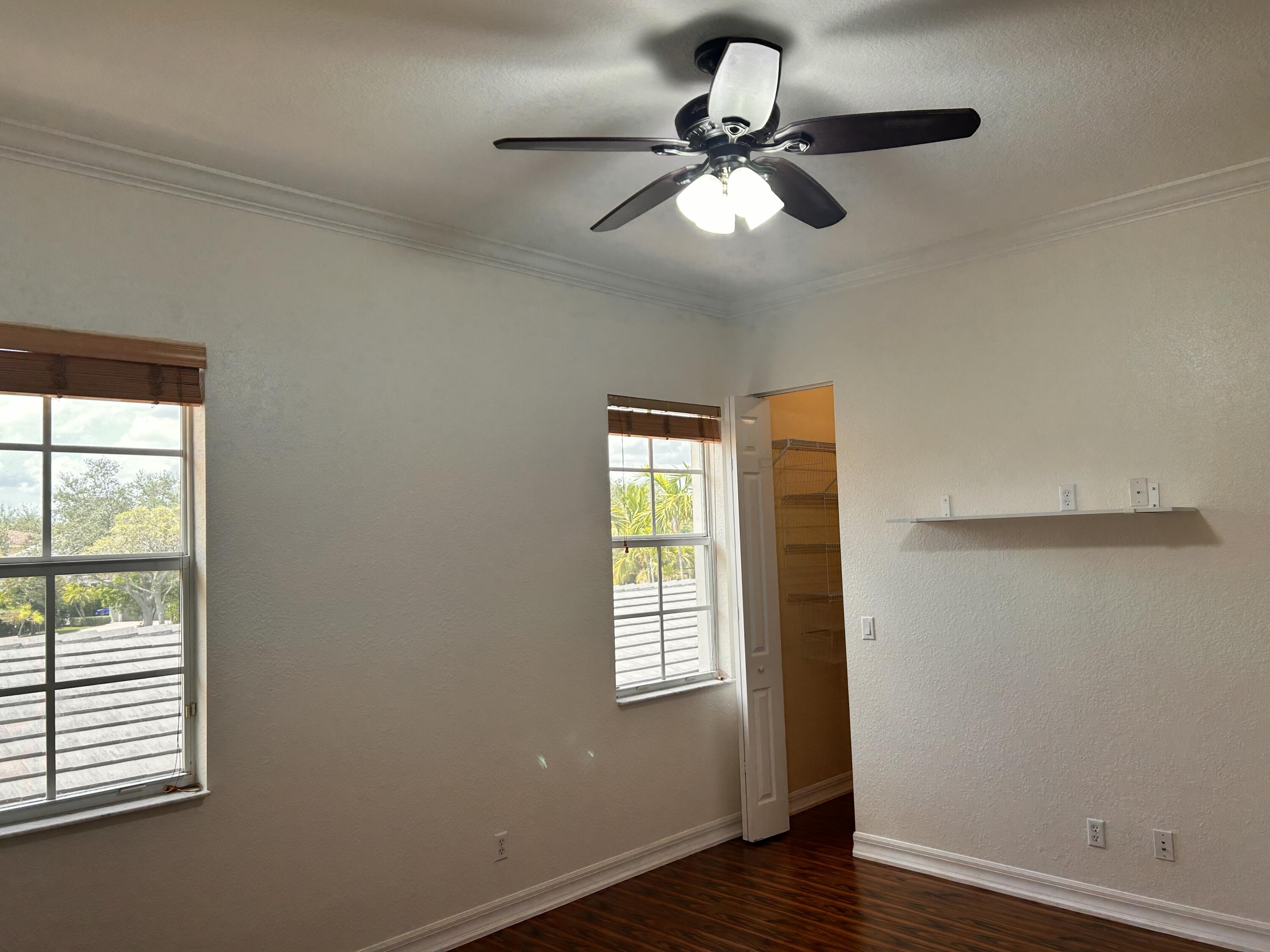 134 Ennis Lane Jupiter, FL 33458 - Photo 9 of 19 an empty room with wooden floor fan and windows