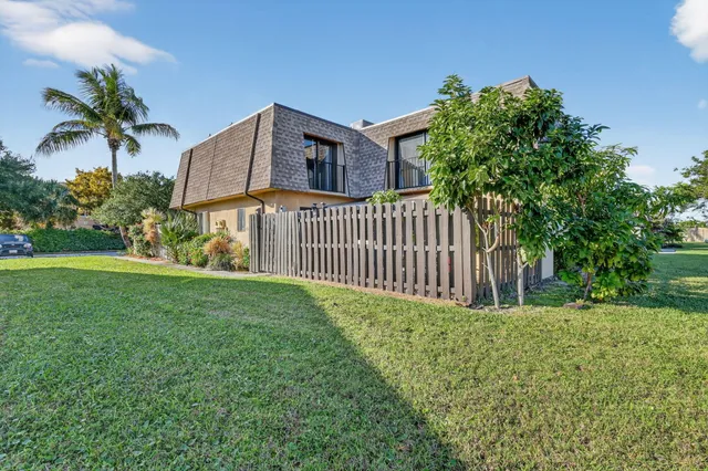 a view of a house with a small yard and a large tree