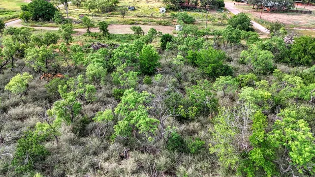 an aerial view of residential house with outdoor space and trees all around