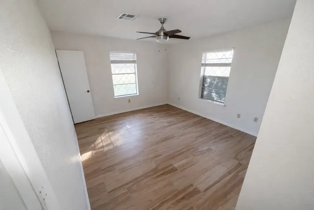 a view of an empty room with a window and wooden floor