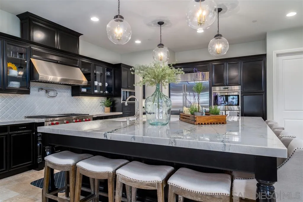 8920 Via Rancho Cielo Rancho Santa Fe, CA 92067 - Photo 6 of 25 a kitchen with stainless steel appliances granite countertop a table chairs sink and stove