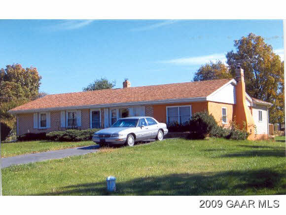 a front view of a house with a garden and trees