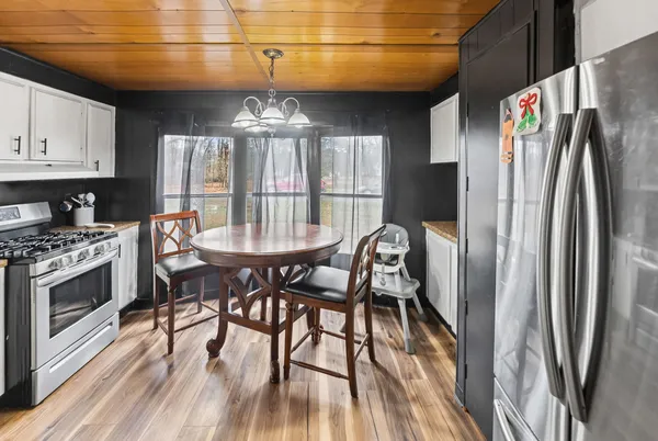 a kitchen with stainless steel appliances granite countertop a dining table chairs and a refrigerator