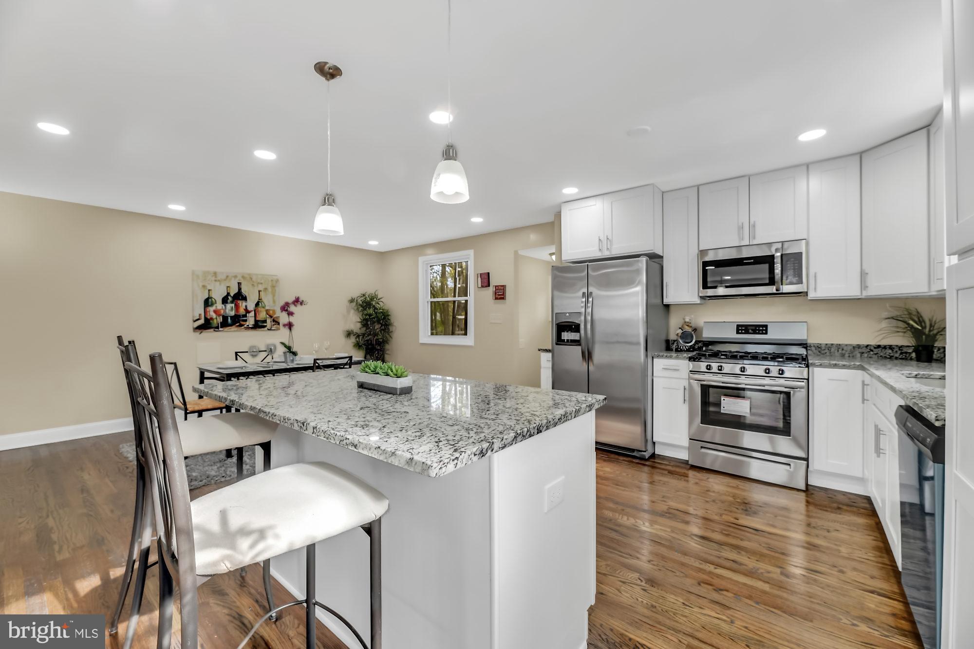 3713 Cassen Road Randallstown, MD 21133 - Photo 7 of 27 a kitchen with stainless steel appliances kitchen island granite countertop a dining table chairs stove refrigerator and microwave