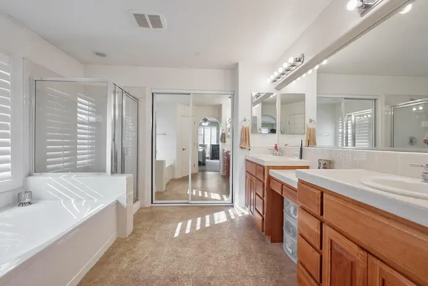 a spacious bathroom with a tub sink shower and mirror