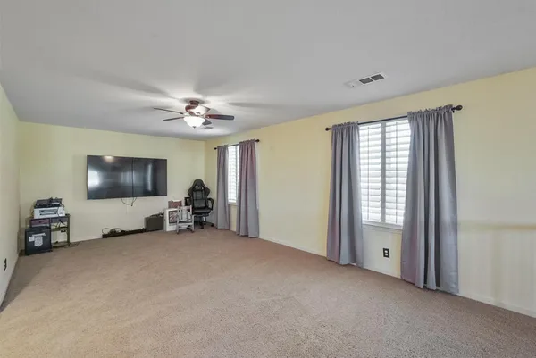 a view of a livingroom with a flat screen tv ceiling fan and windows
