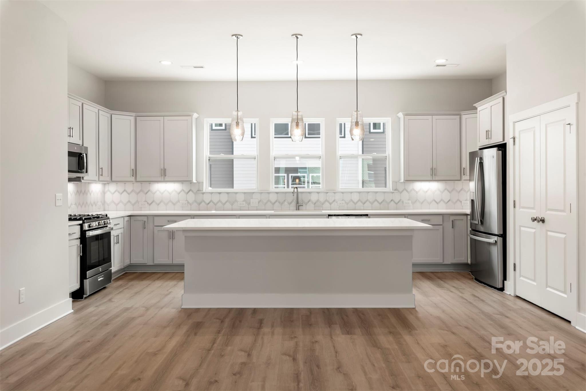 a large white kitchen with kitchen island white cabinets and stainless steel appliances