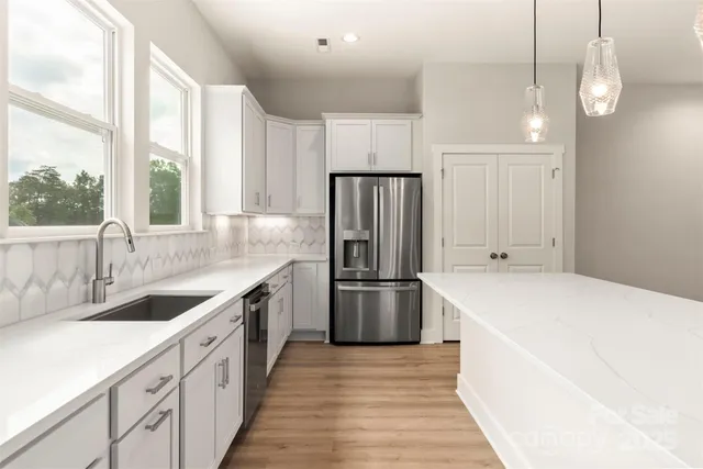 a kitchen with a sink a counter top space stainless steel appliances cabinets and a large window