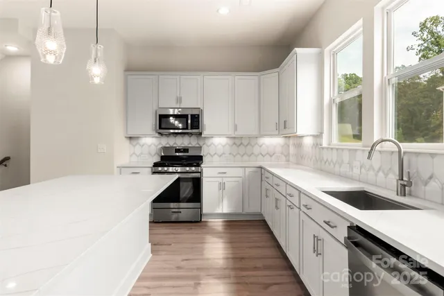 a kitchen with stainless steel appliances granite countertop a sink a stove and a refrigerator