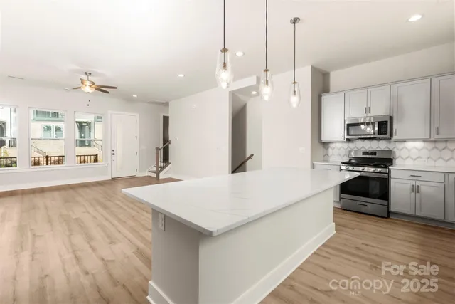 a large kitchen with kitchen island a stove a sink dishwasher and a refrigerator with wooden floor