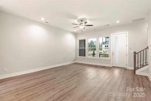 an empty room with wooden floor and a ceiling fan