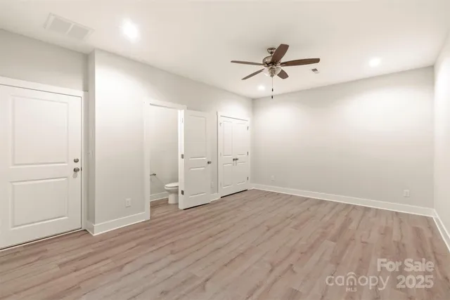 an empty room with wooden floor ceiling fan and windows