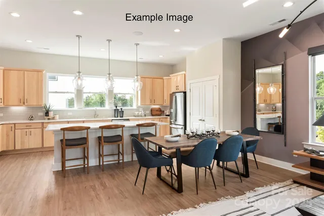 a dining room with stainless steel appliances granite countertop a table chairs a sink and dishwasher a refrigerator with wooden floor