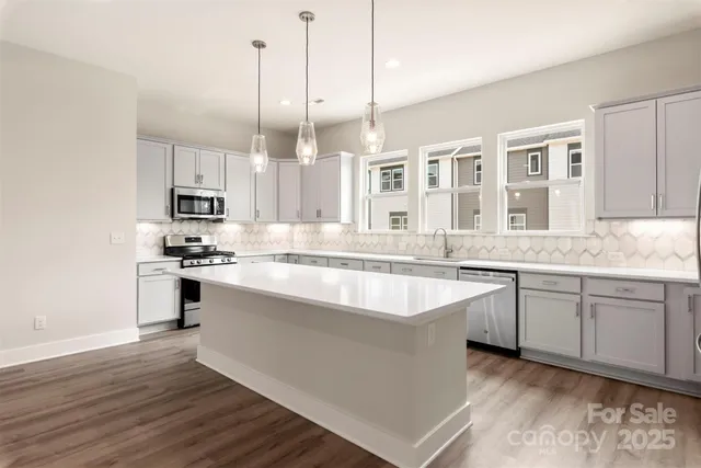 a large kitchen with granite countertop a sink counter space stainless steel appliances and cabinets