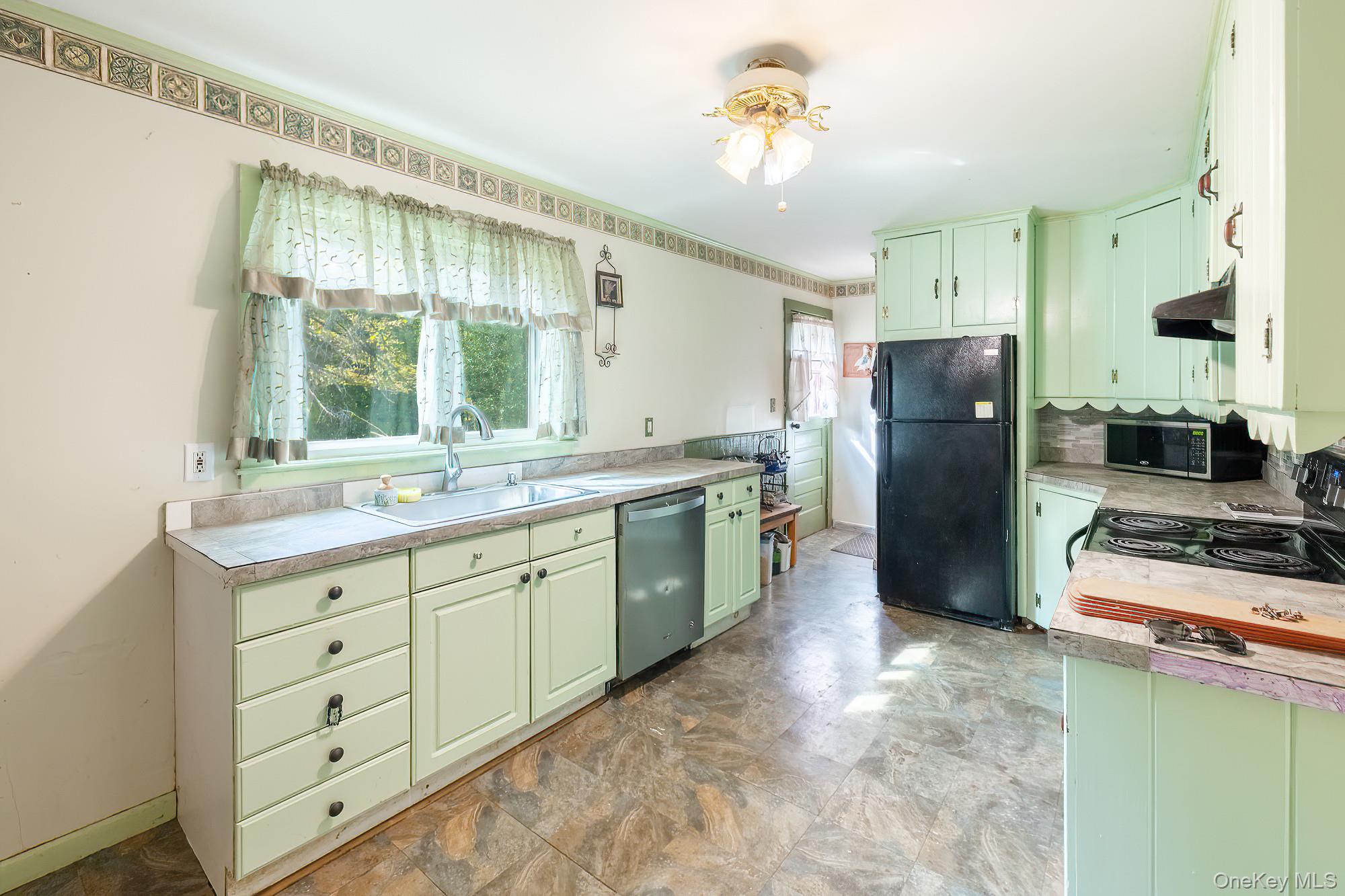 240 Stevers Crossing Road Hudson, NY 12534 - Photo 4 of 21 Kitchen with green cabinetry, black appliances, light countertops, stone finish floors, and under cabinet range hood