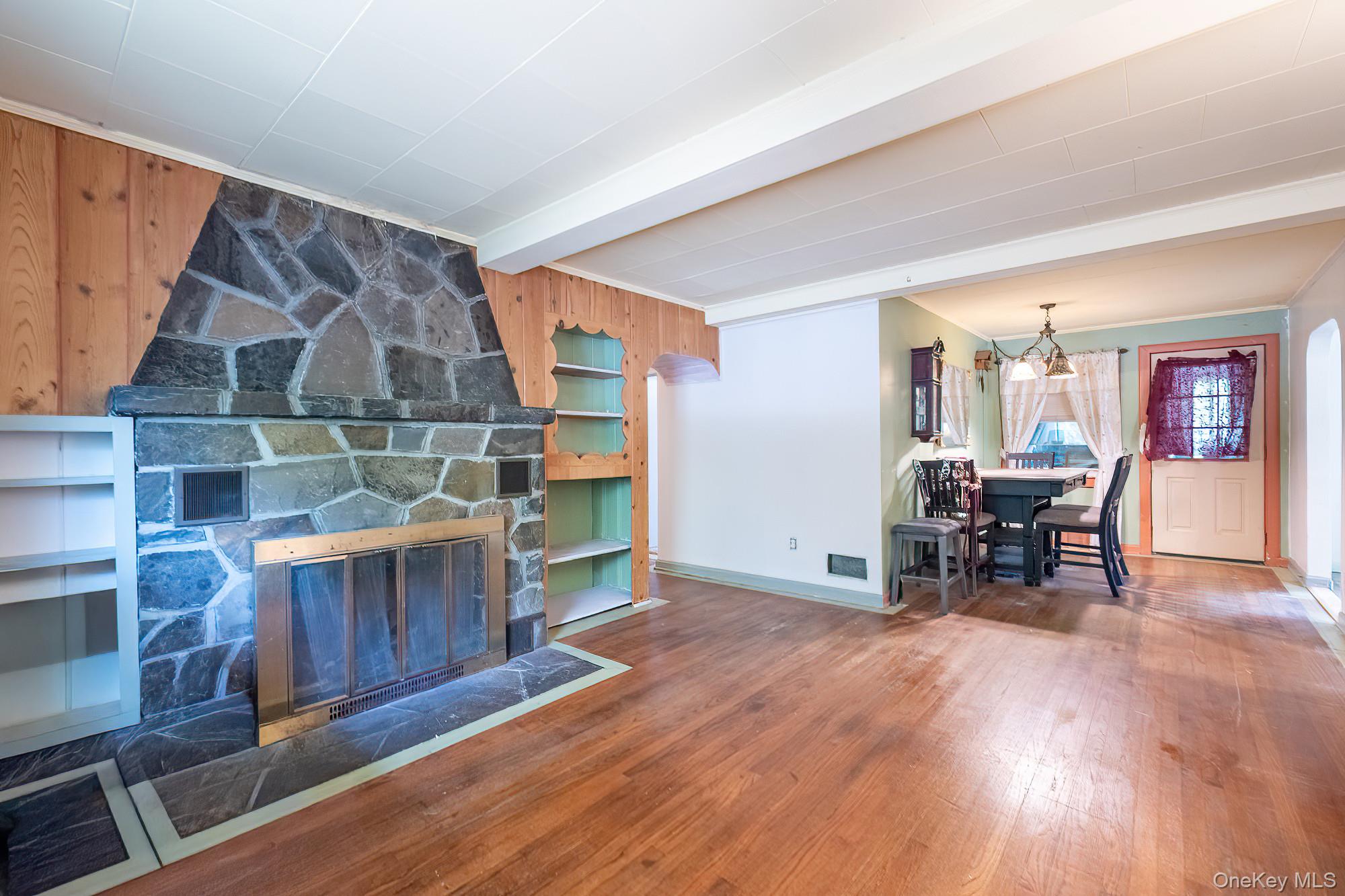 240 Stevers Crossing Road Hudson, NY 12534 - Photo 8 of 21 Living room featuring wood-type flooring, a stone fireplace, beam ceiling, and wood walls