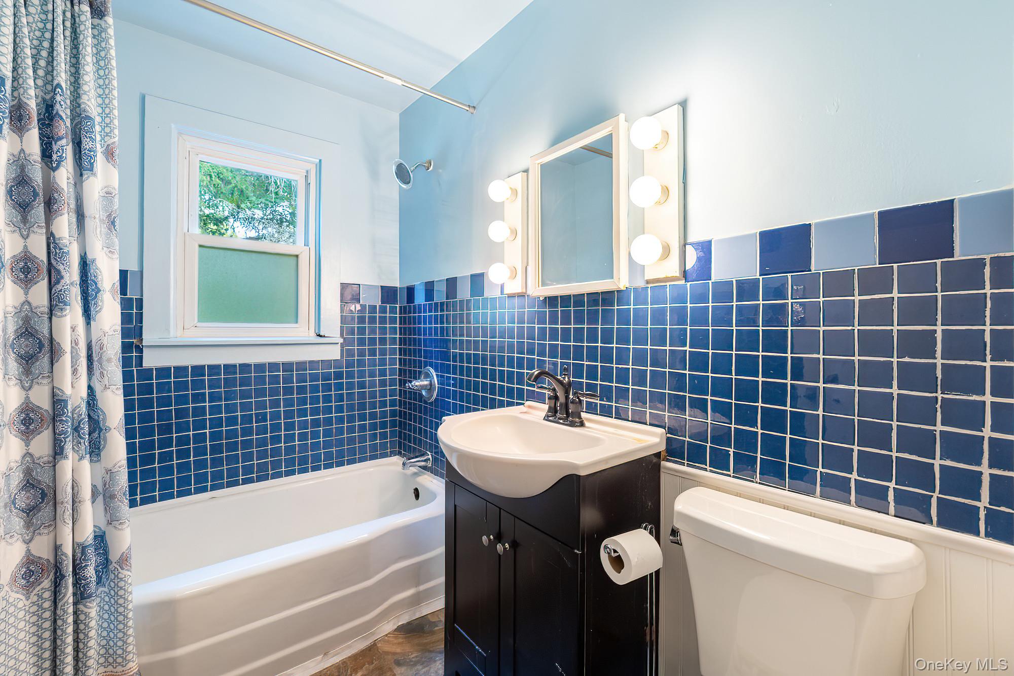 240 Stevers Crossing Road Hudson, NY 12534 - Photo 9 of 21 Full bath featuring shower / bath combo with shower curtain, tile walls, wainscoting, and vanity