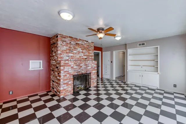 a living room with a black white checkered floor with a fireplace and a chandelier