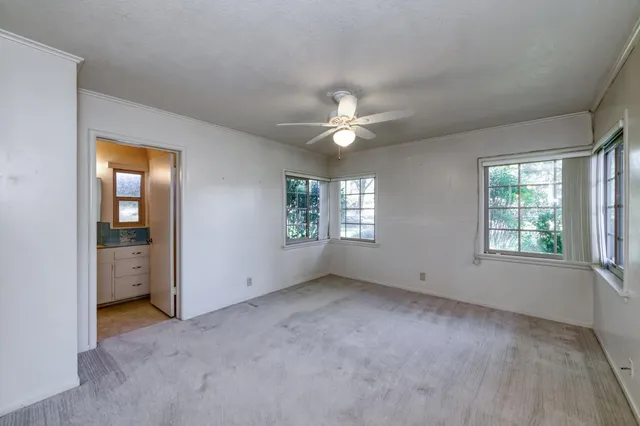 an empty room with windows and fan