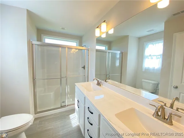 a spacious bathroom with a granite countertop sink a toilet a mirror and shower