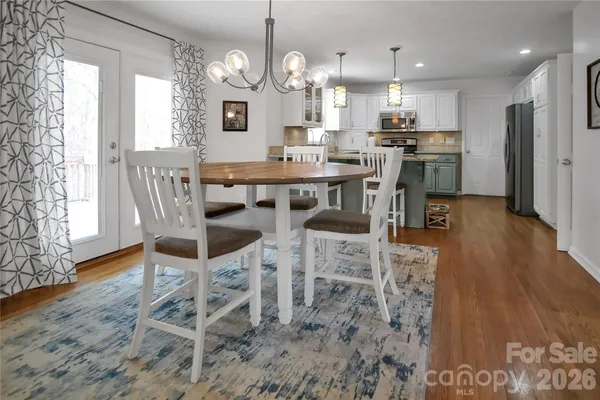 a kitchen with stainless steel appliances granite countertop a stove top oven a refrigerator a sink and a dining table with wooden floor