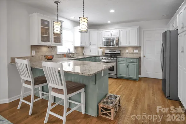 a kitchen with stainless steel appliances a dining table chairs microwave and sink