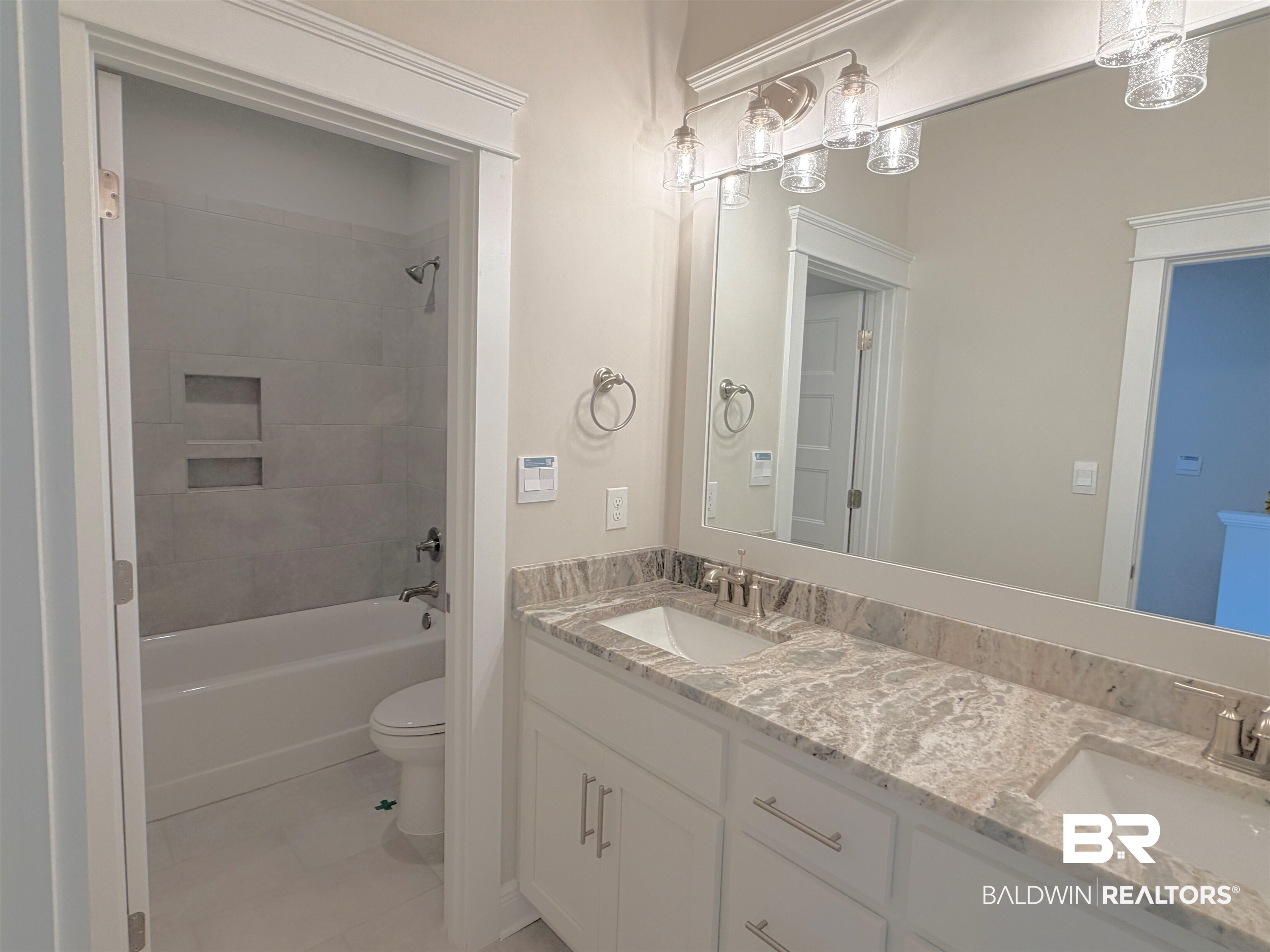 318 Morning Mist Way Fairhope, AL 36532 - Photo 13 of 20 Double vanity with a patterned countertop and undermount sinks, featuring a large wall-mounted mirror and a four-light fixture