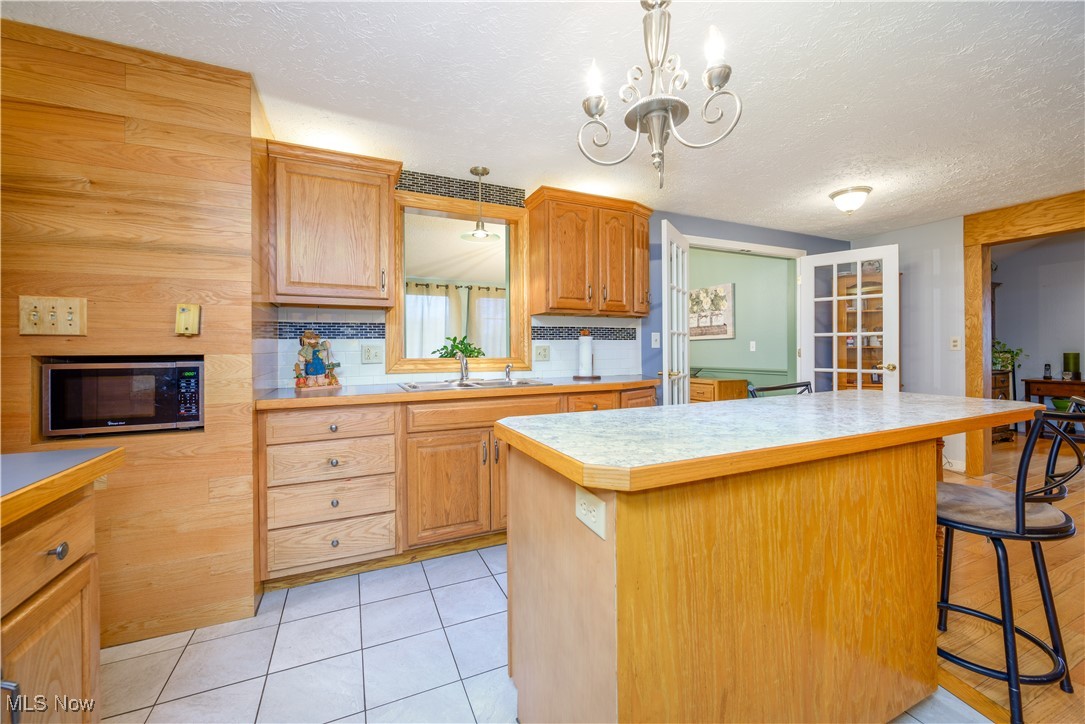 17080 Heiser Road Berlin Center, OH 44401 - Photo 23 of 35 Kitchen with tasteful backsplash, sink, decorative light fixtures, a kitchen island, and a breakfast bar area