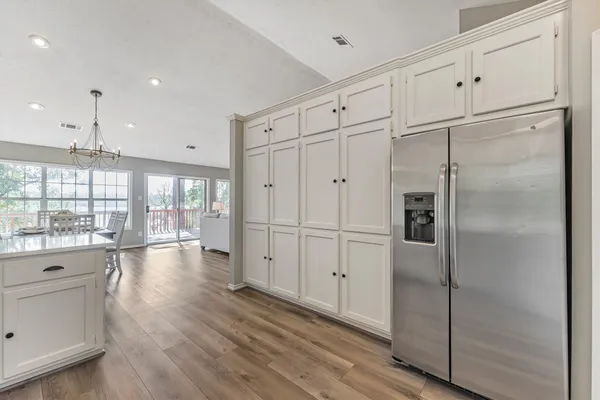 a open kitchen with granite countertop a refrigerator and white cabinets