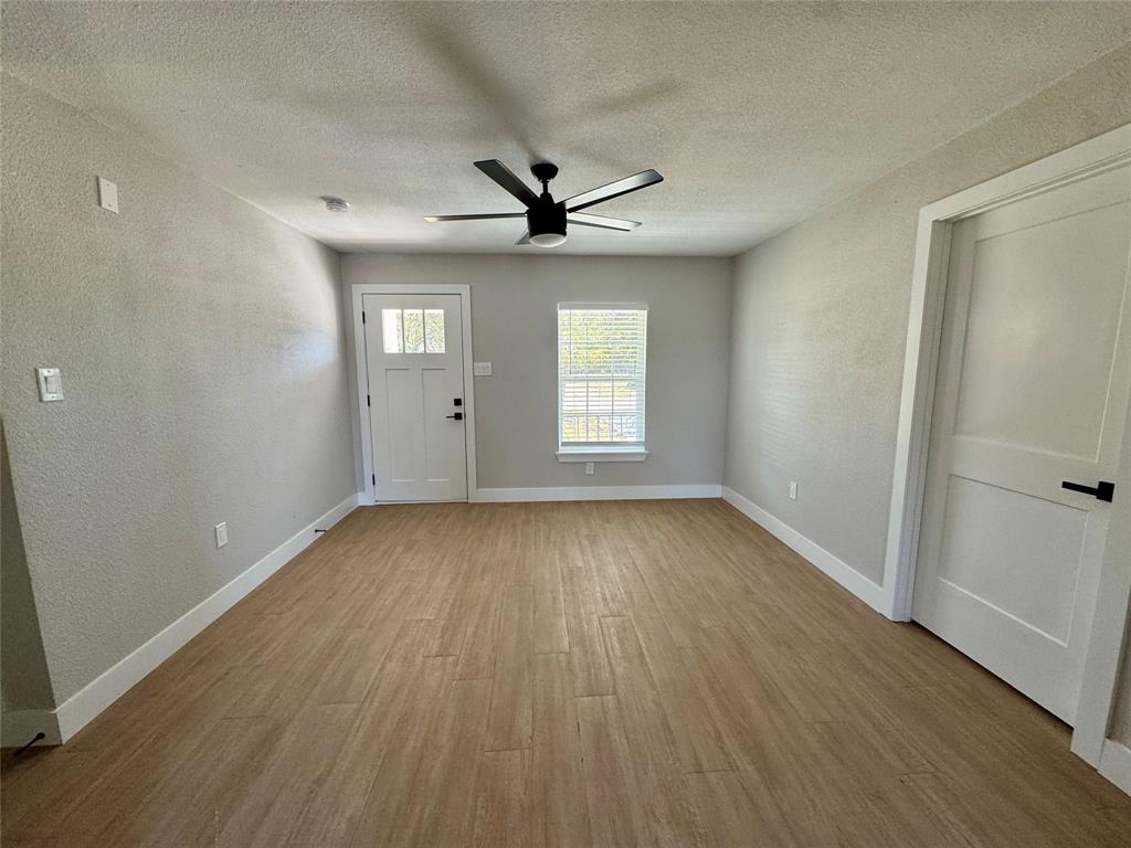 3824 Patman Street Lancaster, TX 75134 - Photo 11 of 24 an empty room with wooden floor chandelier fan and windows