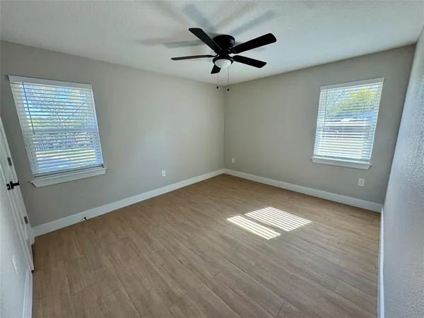 a view of an empty room with a window and wooden floor