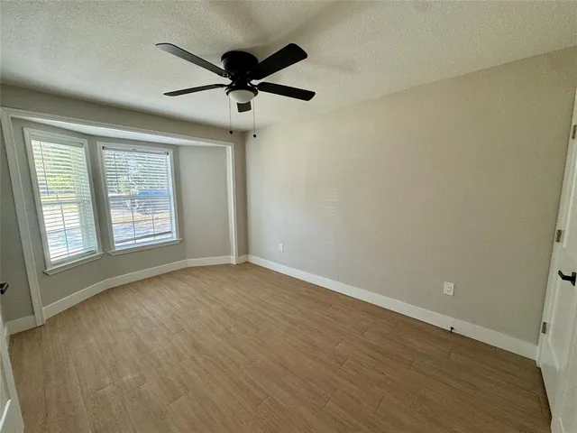 a view of an empty room with a window and wooden floor