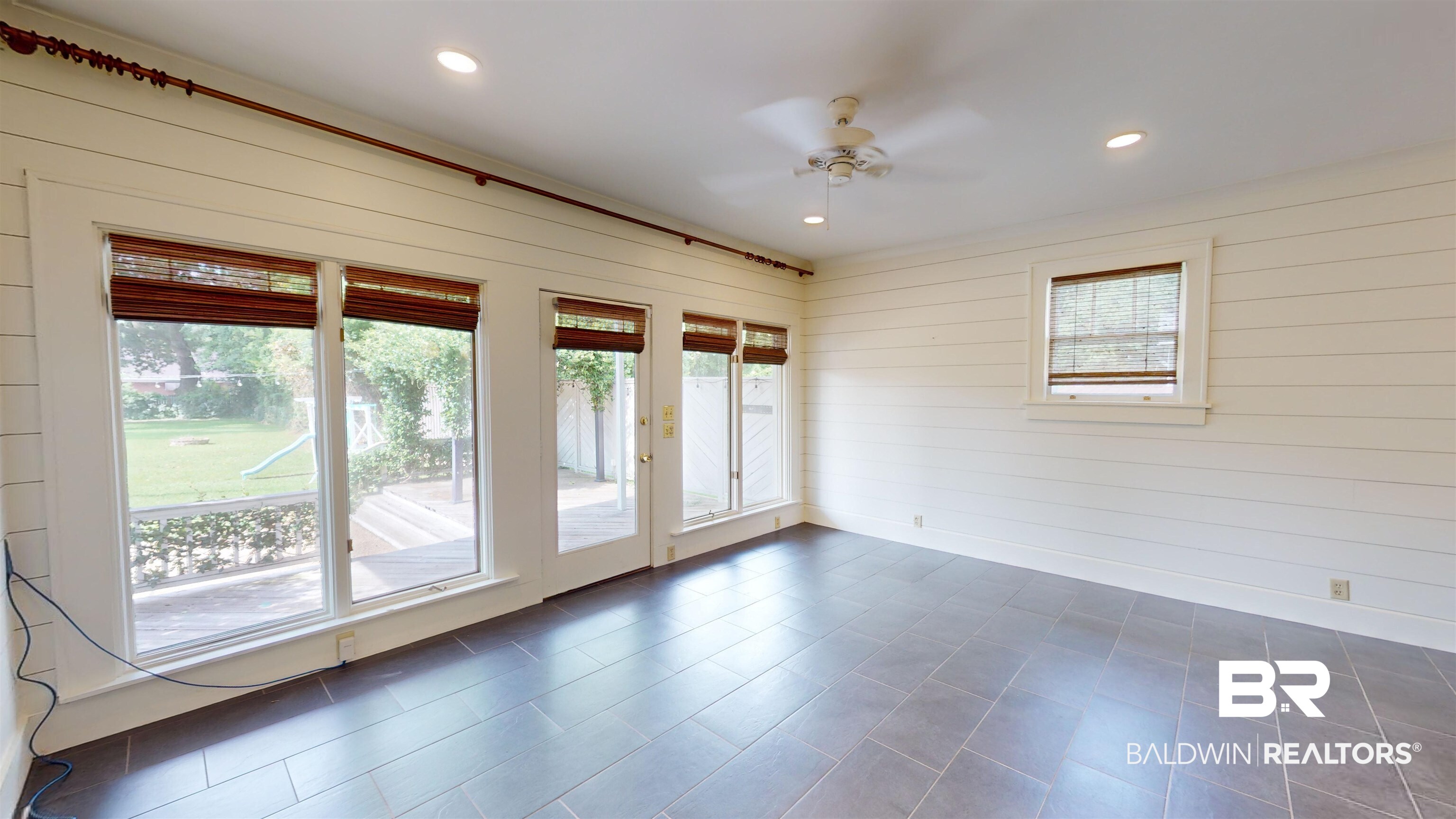 4307 Stein Street Mobile, AL 36608 - Photo 12 of 28 Empty room with dark tile patterned flooring, a healthy amount of sunlight, ceiling fan, and wooden walls