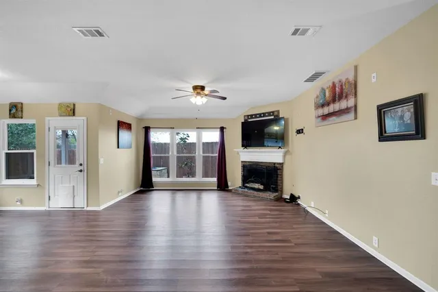 a view of a livingroom with wooden floor a fireplace and window