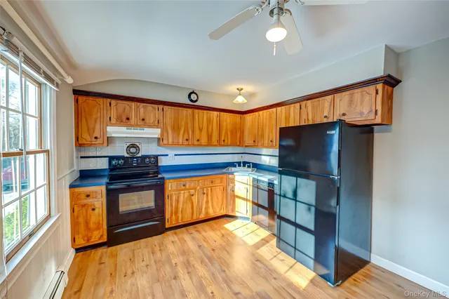 a kitchen with stainless steel appliances granite countertop a refrigerator a sink dishwasher a stove and a dining table with wooden floor