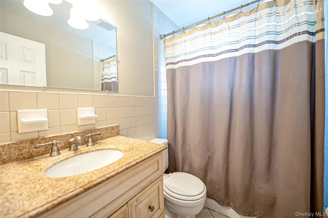 a bathroom with a granite countertop sink toilet and a mirror
