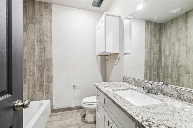 a bathroom with a granite countertop sink toilet and shower