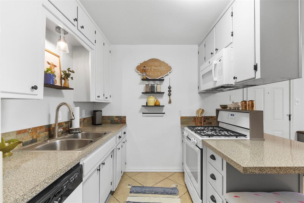 708 East Prairie View Road Crowley, TX 76036 - Photo 9 of 21 Galley kitchen featuring white cabinetry, stone-look countertops, and a full-height backsplash with varied natural stone textures