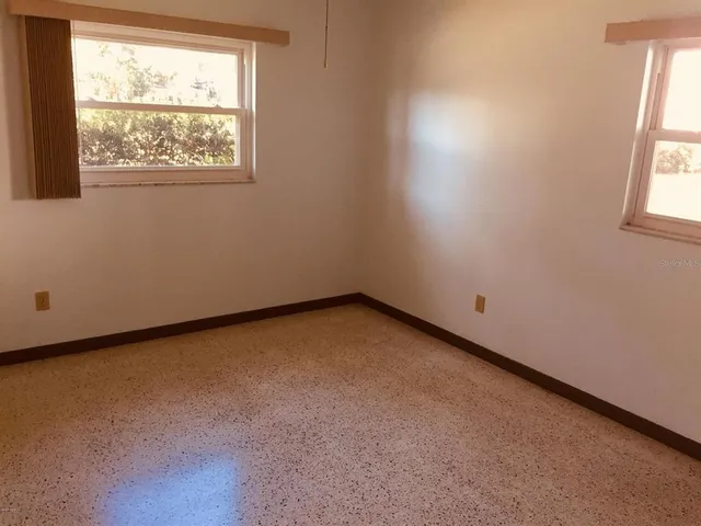 an empty room with windows and fan