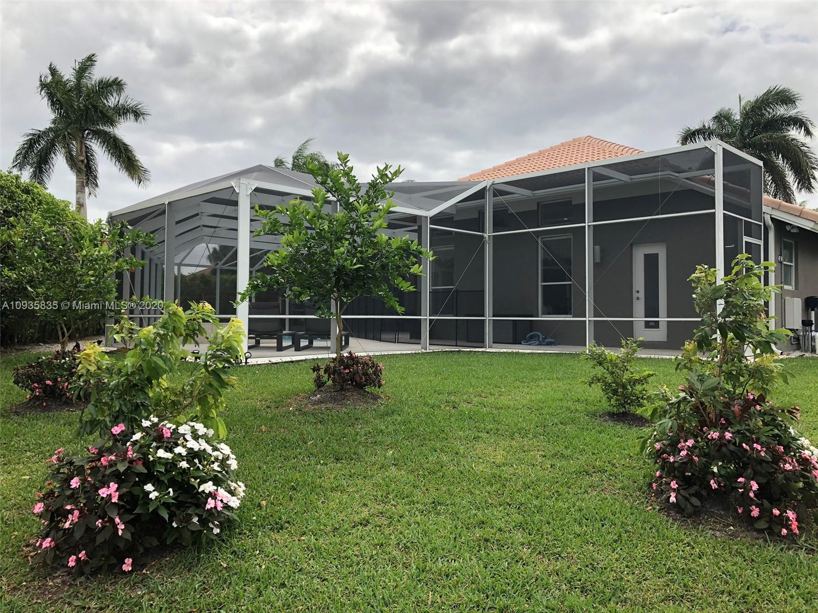 Boca Isles Boca Raton, FL 33498 - Photo 16 of 17 a view of a house with a flower garden and a bench